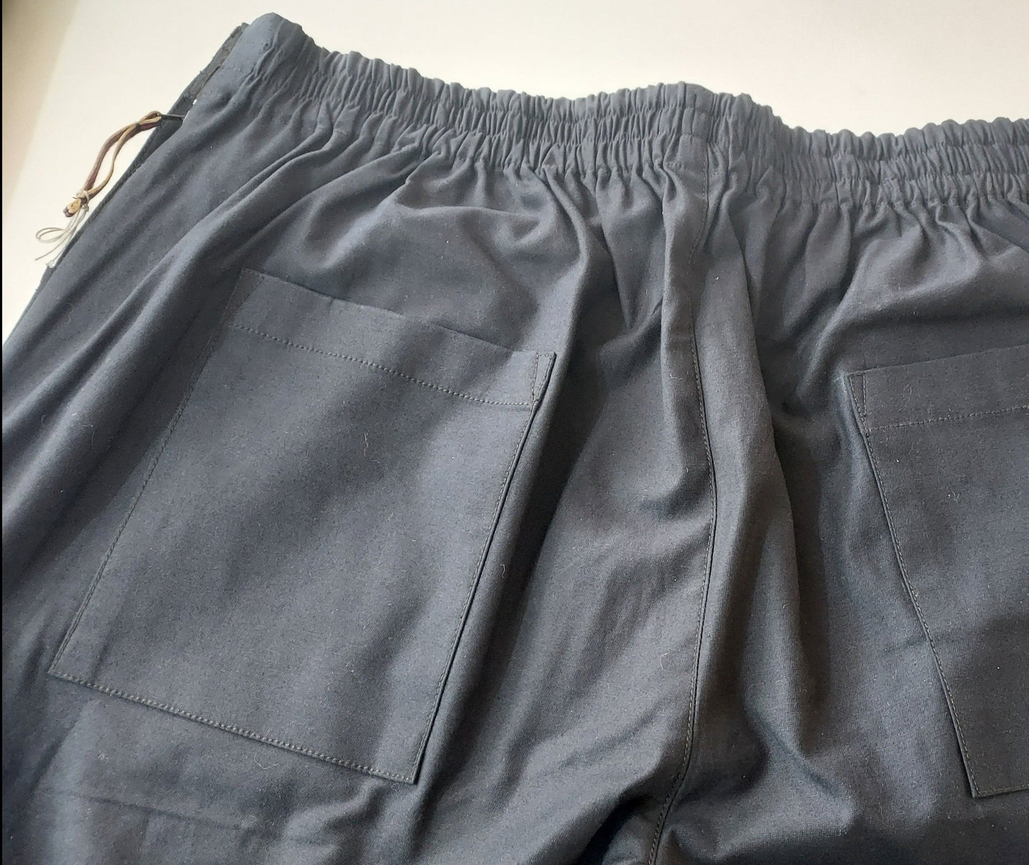 Back side of the trouser is shown with two patch pockets , elastic on the waist and zipper puller on the wearer's left